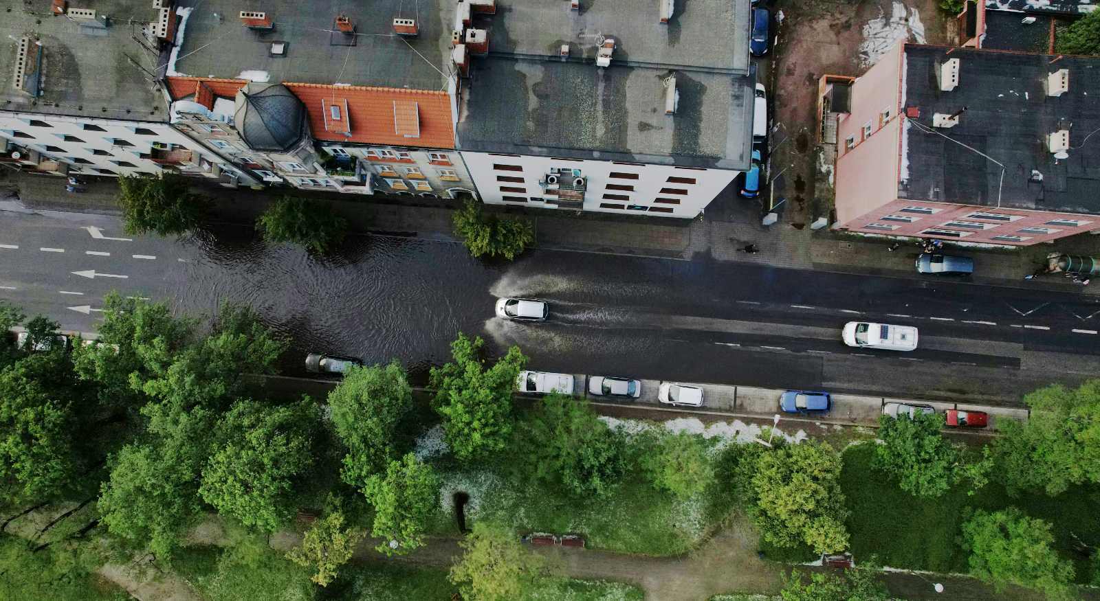 View of a flooded street in a city with cars moving through the water